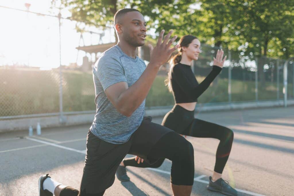 Two individuals engaging in outdoor exercise, performing lunges under natural sunlight. This image represents Key Healthcare’s focus on incorporating nutrition and exercise into adolescent mental health recovery, promoting physical fitness, healthy habits, and emotional well-being as part of a holistic approach to treatment.