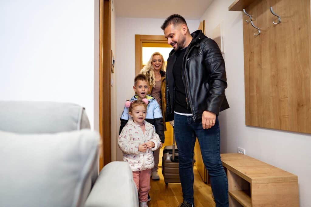 A happy family of four entering a warm and welcoming home, symbolizing Key Healthcare’s focus on family-centered treatment. This image reflects the importance of engaging parents, guardians, and siblings in adolescent mental health recovery through family therapy, support, and collaborative care plans tailored to each teen’s unique needs.