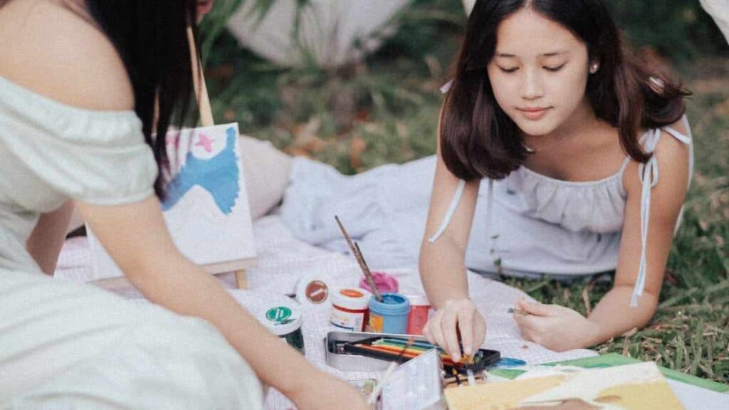 Teen girls engaged in outdoor art therapy, illustrating complementary and emerging treatments for adolescent mental health.