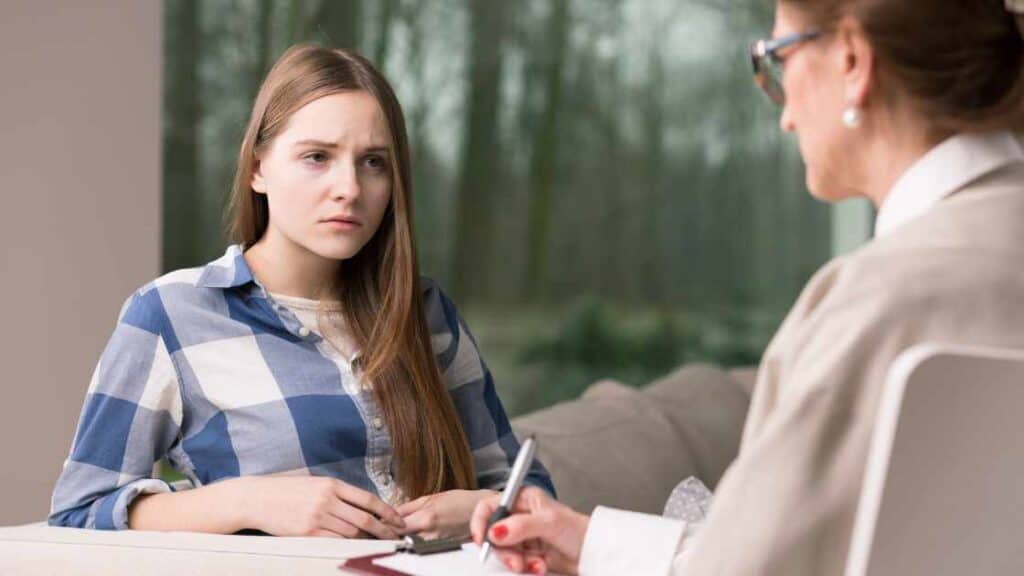 Teen girl in therapy session with a concerned expression, illustrating core treatment approaches for adolescent depression.