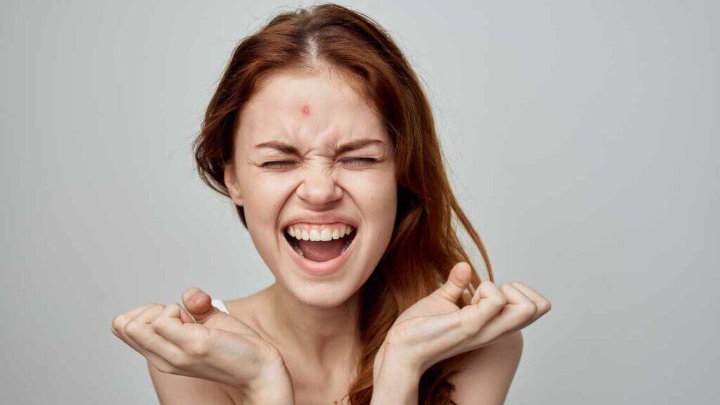 Frustrated teen girl with clenched fists and closed eyes, reflecting emotional distress as an early sign of adolescent depression.
