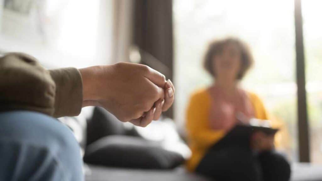 Teen girl nervously wringing hands during therapy session, symbolizing support in residential treatment for teen girls.
