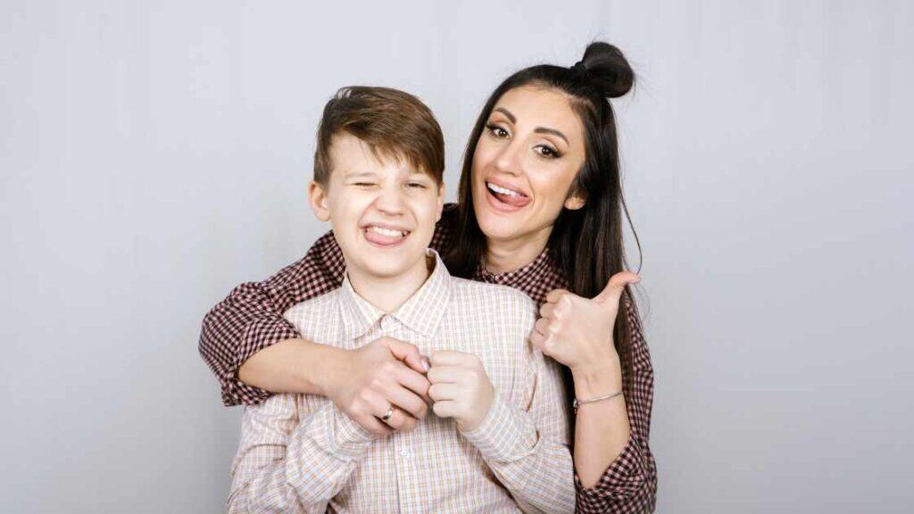 Smiling teen boy and supportive woman pose playfully, symbolizing positive outcomes of early and effective mental health treatment.